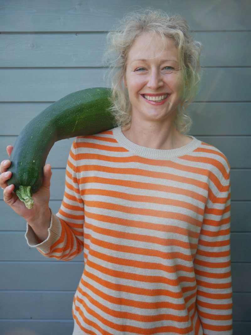 Frau mit großer Zucchini über der Schulter